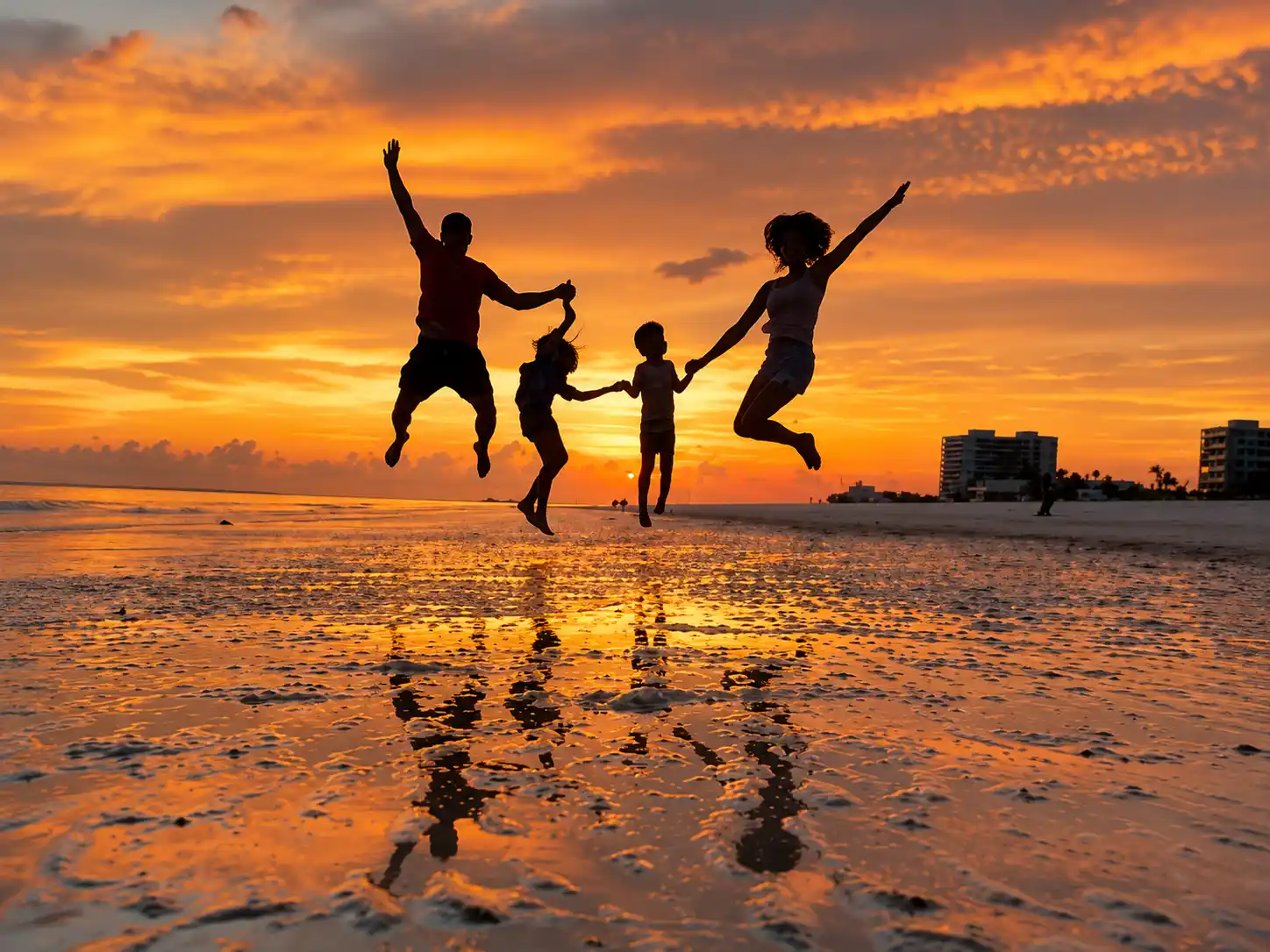 Family playing on the beach at sunset