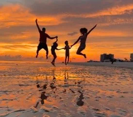 Family playing on the beach at sunset